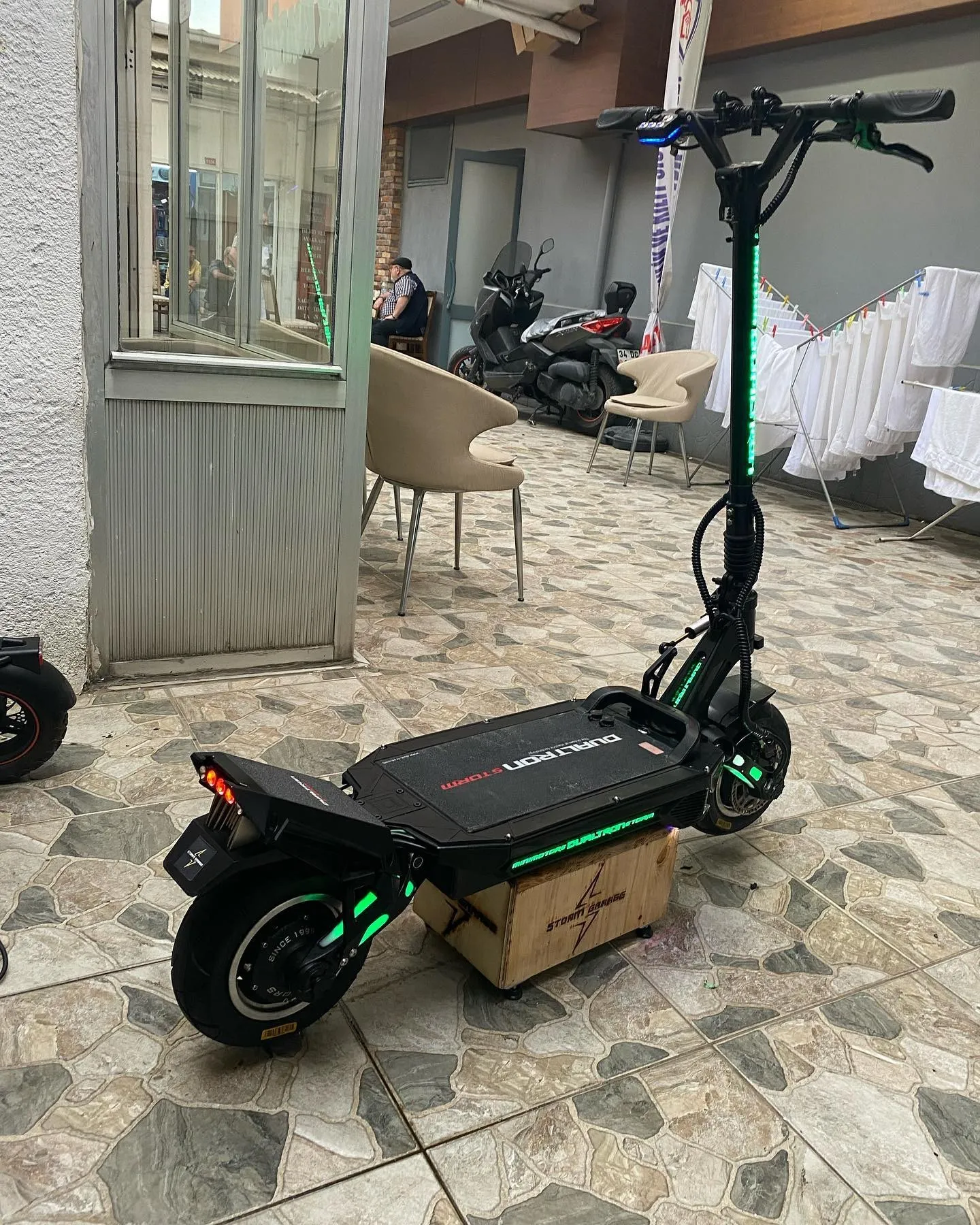 Yeşil LED şeritli Dualtron Storm, mozaik zeminli pasajda Storm Garage kasası üzerinde