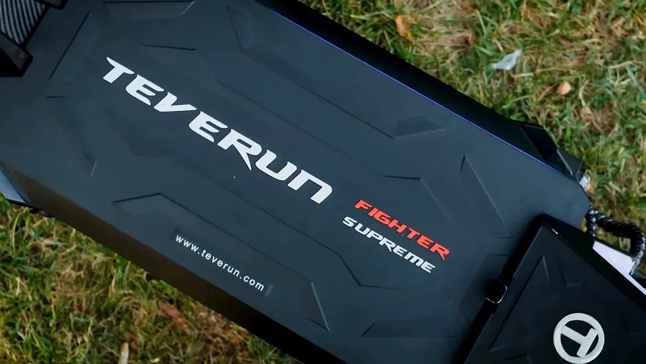 Teverun scooter gövdesindeki TEVERUN FIGHTER SUPREME yazısı yakın plan, kenarda çimen