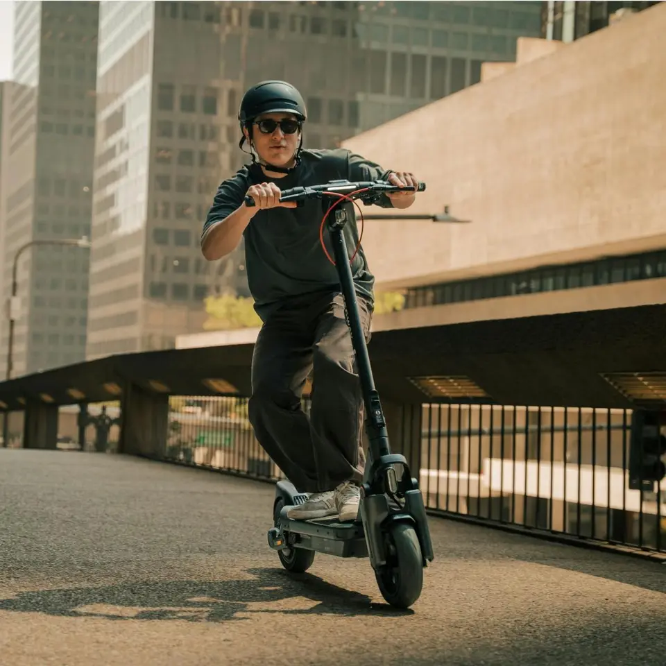 Kasklı sürücü Segway Max G3 ile şehirde beton bir köprü üzerinde ilerliyor