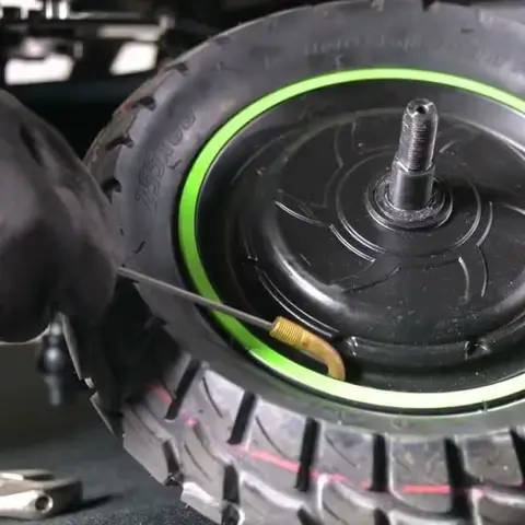 Hub motorlu scooter tekerinde lastik değişimi: yeşil jant bandı, aks ve pirinç sibop yakın plan