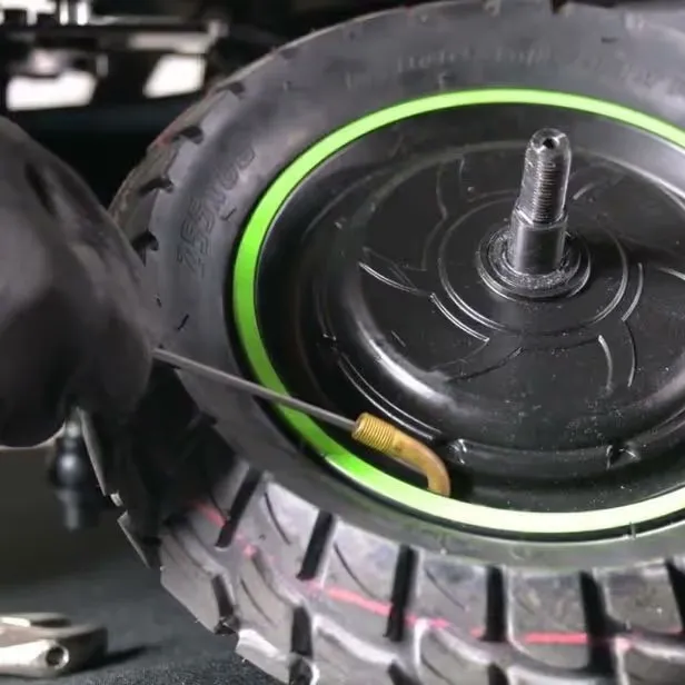 Hub motorlu scooter tekerinde lastik değişimi: yeşil jant bandı, aks ve pirinç sibop yakın plan