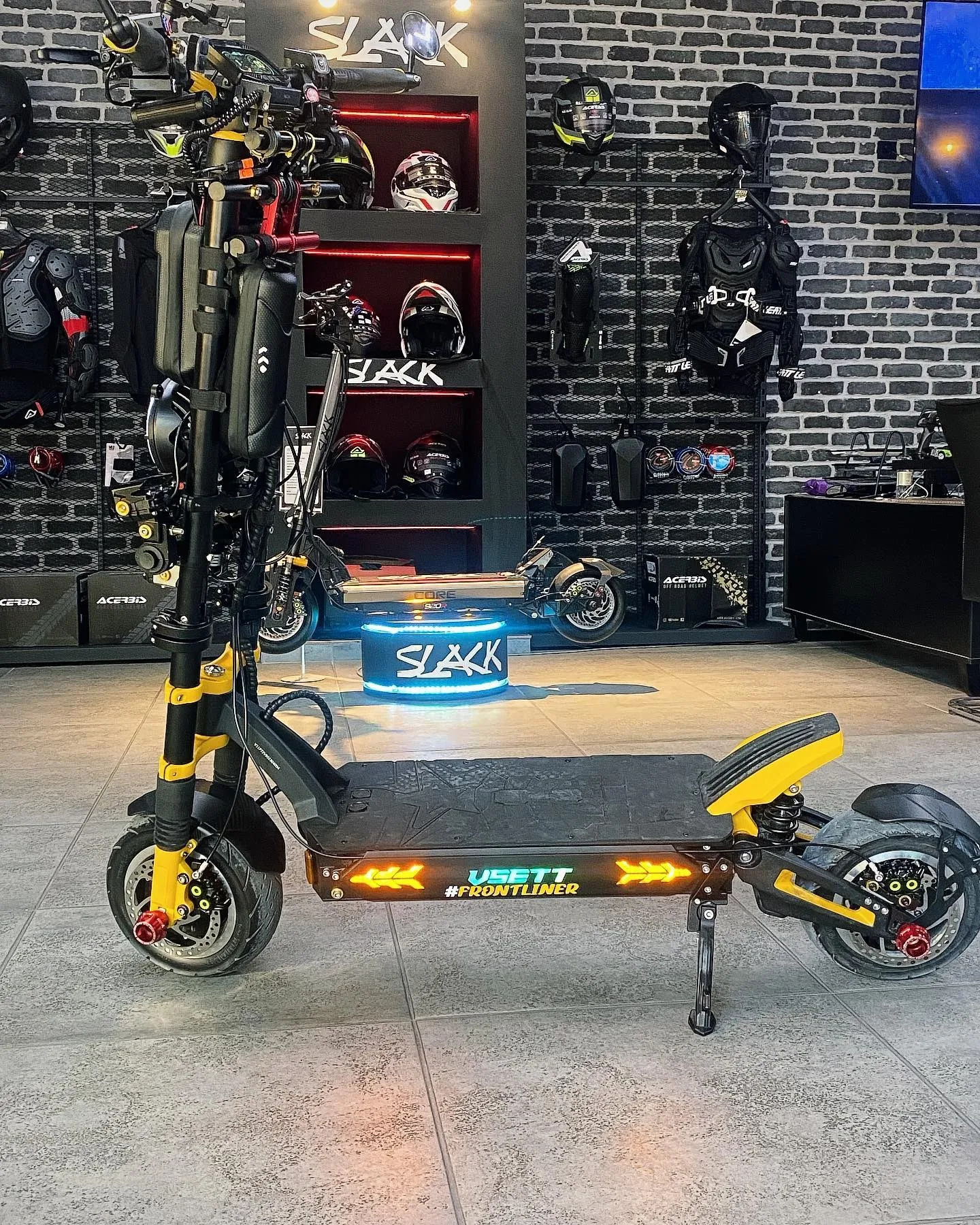 Sarı detaylı VSETT Super72 scooter, siyah tuğla duvarlı bir mağazada; bu cihaza Magura fren adaptasyonu yapıldı