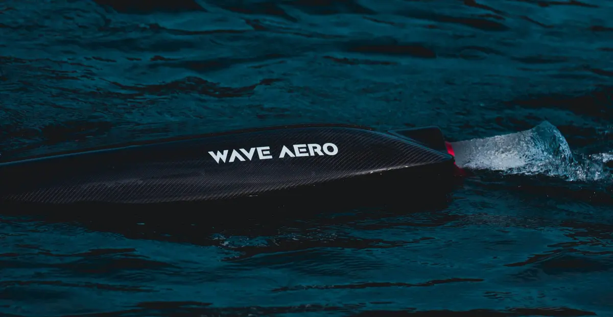 Wave Aero Carbon V1 karbon jetboard, koyu renkli suda arkasında su sıçratarak ilerliyor