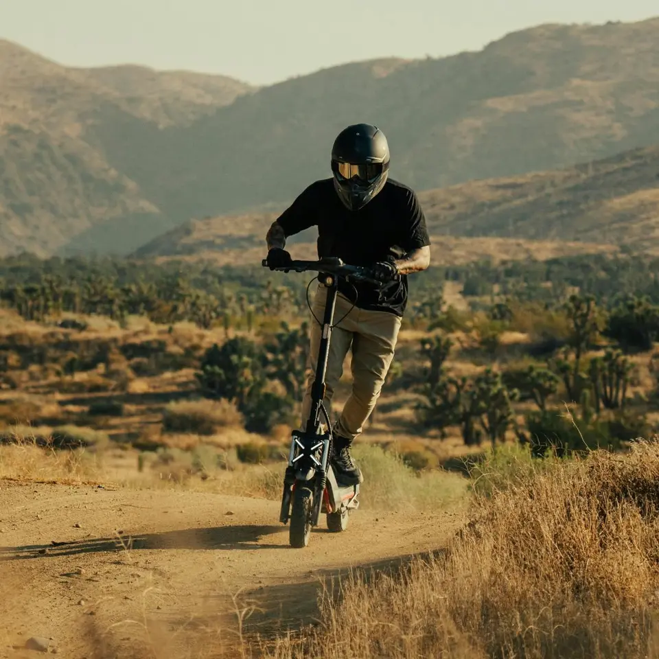Kasklı sürücü Segway ZT3 Pro ile çöl manzarasında toprak yolda ilerliyor